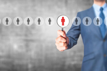 Mann zeigt mit Lupe auf Figur