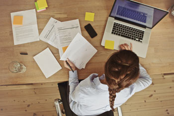 Frau mit Laptop und Unterlagen von oben