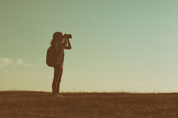 Frau mit Rucksack schaut durch Fernglas