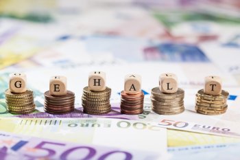 Münztürme nebeneinander, auf denen jeweils ein Buchstabenwürfel steht, die zusammen das Wort Gehalt ergeben