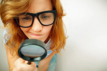 Studentin schaut durch Lupe