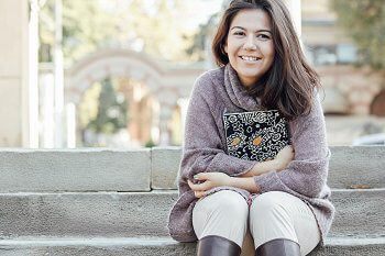 Studentin sitzt auf Treppe und lächelt