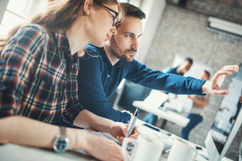 Eine duale Studentin für Gesundheitsökonomie wird im Unternehmen von einem Kollegen eingearbeitet.