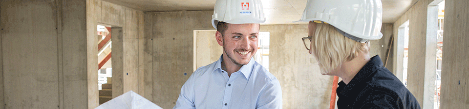 Zwei Mitarbeiter von HEBERGER stehen auf einer Baustelle und sehen sich einen Bauplan